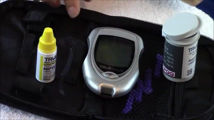 A hand rolling a control solution bottle between the palms to mix it, with the glucometer and test strip container nearby.