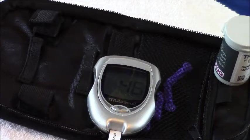 TRUEresult glucometer displaying a reading of 46, with the test strip inserted and the carrying case visible.