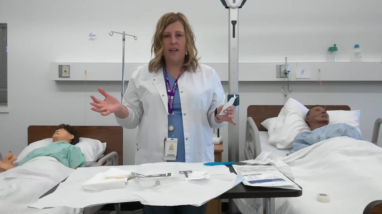 A healthcare professional gestures with both hands, explaining the importance of keeping supplies within the sterile field and away from the border.