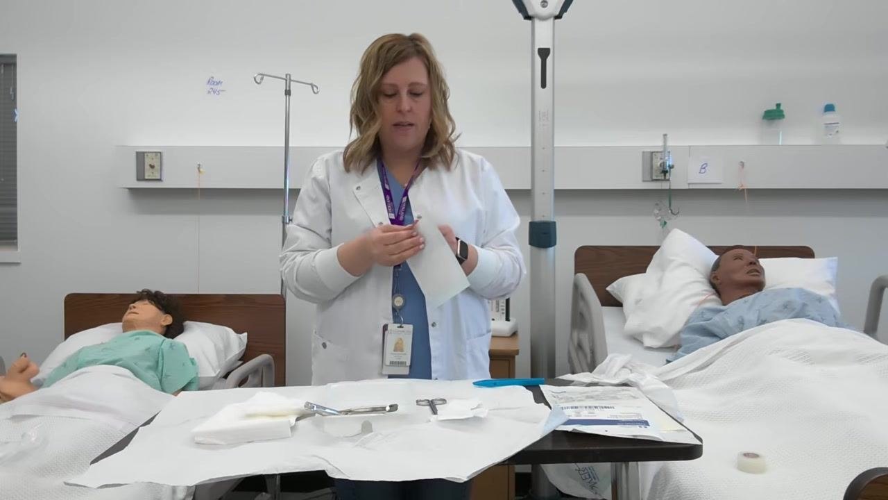 A healthcare professional opens another gauze package, preparing to use forceps while the tray and supplies remain organized within the sterile field.