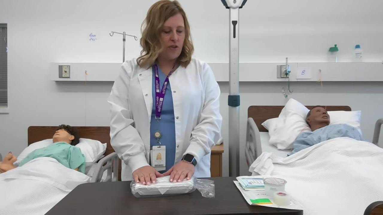 A healthcare professional places both hands on the sealed dressing tray, preparing to inspect and organize the supplies.