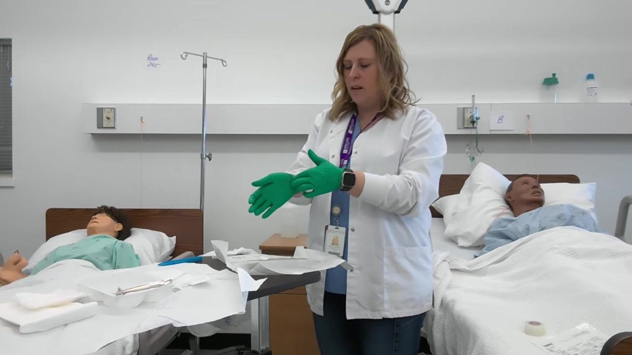 A healthcare professional adjusts the fit of her gloves, ensuring both are properly donned and the cuffs are straightened.