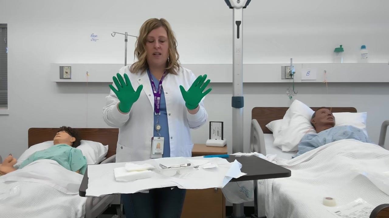 A healthcare professional holds her hands above the tray, preparing to organize supplies. Gauze, forceps, and other sterile items are visible on the tray.