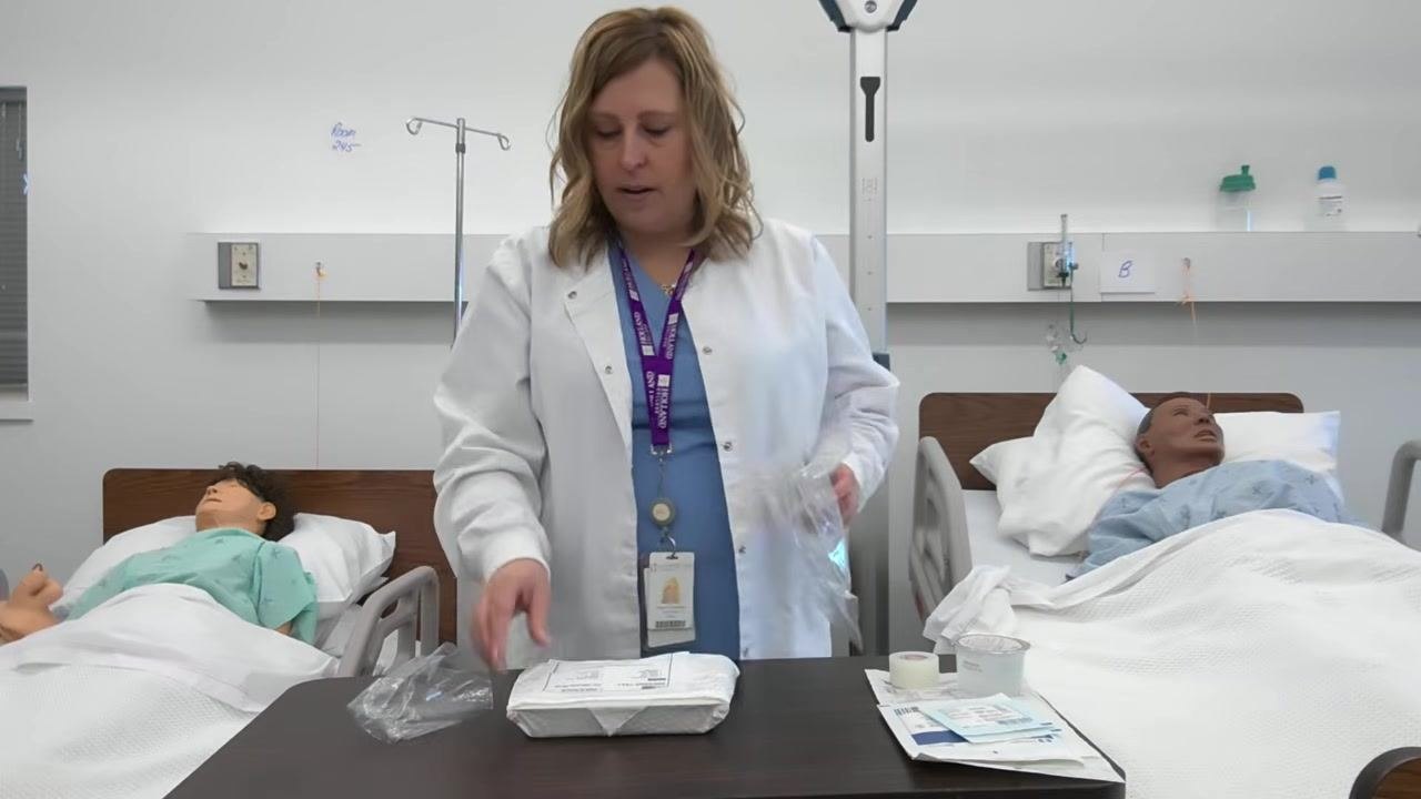 A healthcare professional removes the outer plastic from the dressing tray, preparing to open it.