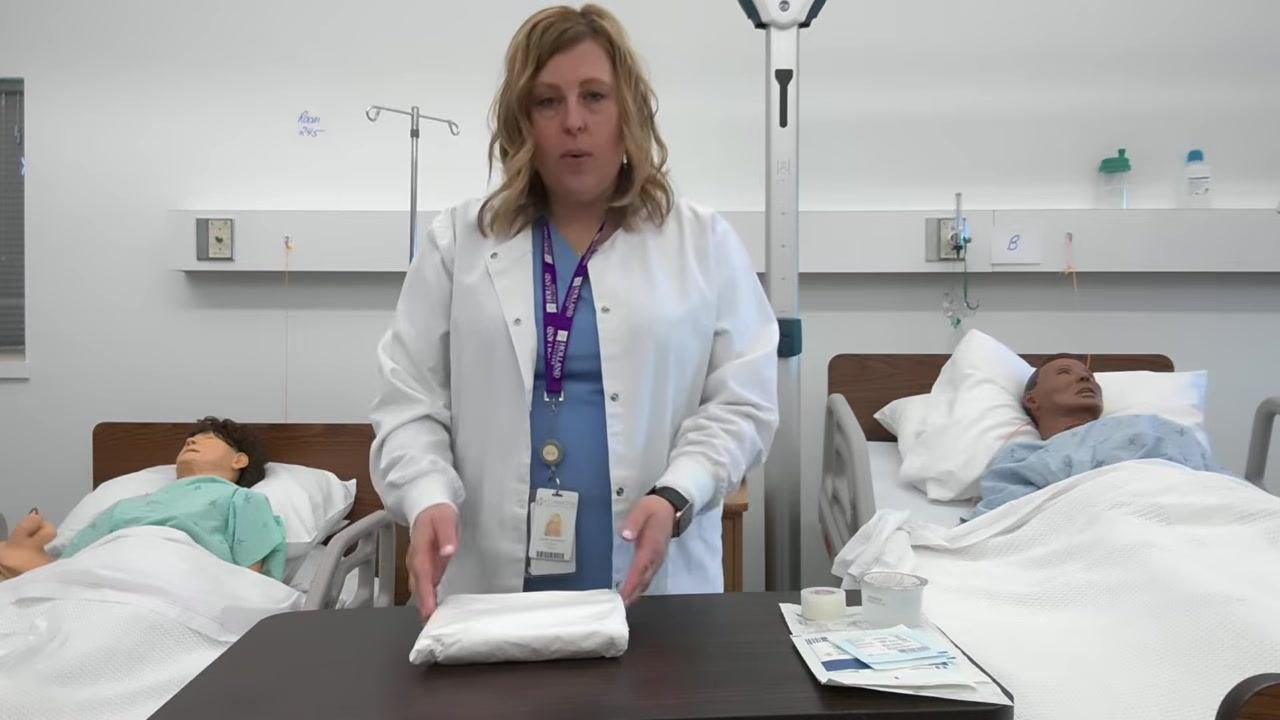 A healthcare professional stands with the unwrapped dressing tray at waist height, ready to proceed.