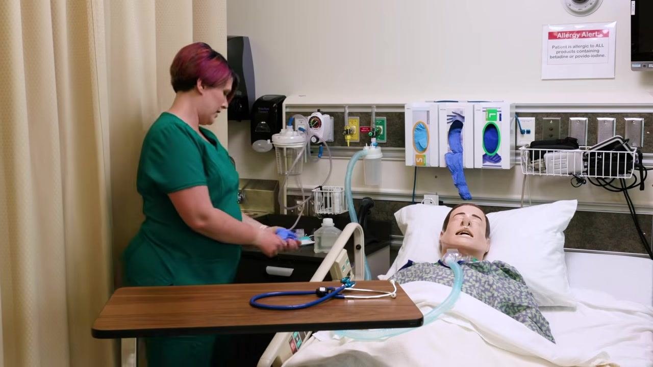 Clinician adjusting patient's gown and bedding, stethoscope on overbed table, ensuring patient comfort