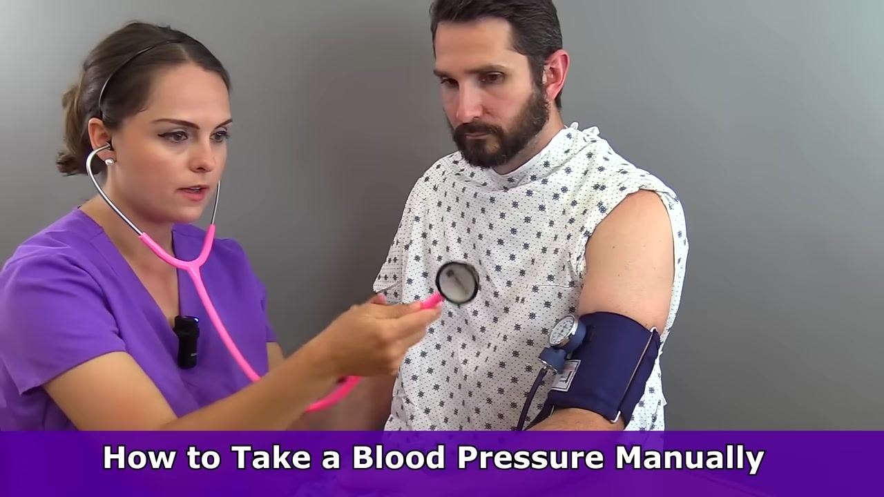 Nurse and patient seated at a table, with the patient's arm at heart level while the nurse explains positioning