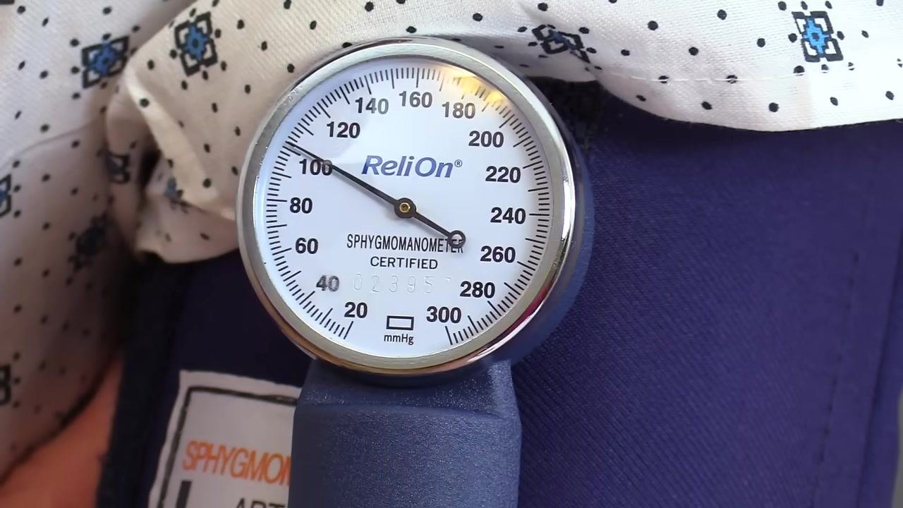 Close-up of a sphygmomanometer gauge showing 100 mmHg, labeled "ReliOn", with a clear needle position