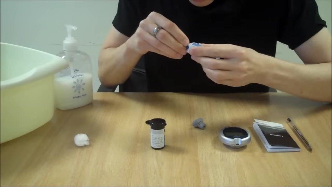 Person inserting a blue lancet into the lancing device, focusing on the loading process