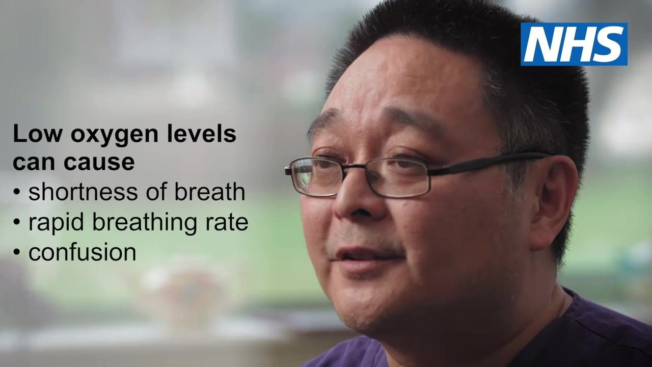 A healthcare professional explaining that low oxygen levels can cause shortness of breath, rapid breathing rate, and confusion.