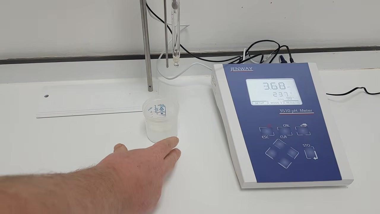 Hand moving the sample beaker away; probes are suspended above the bench, ready for storage; the pH meter display shows 3.68 pH