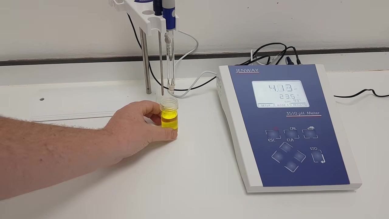 Hand lowering the pH buffer solution (yellow liquid) under the probes, preparing for calibration