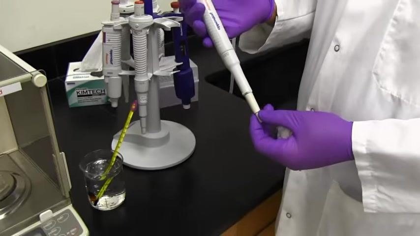 A person in a lab coat and purple gloves holds a pipette, focusing on calibration accuracy, with calibration equipment and pipette stand visible.