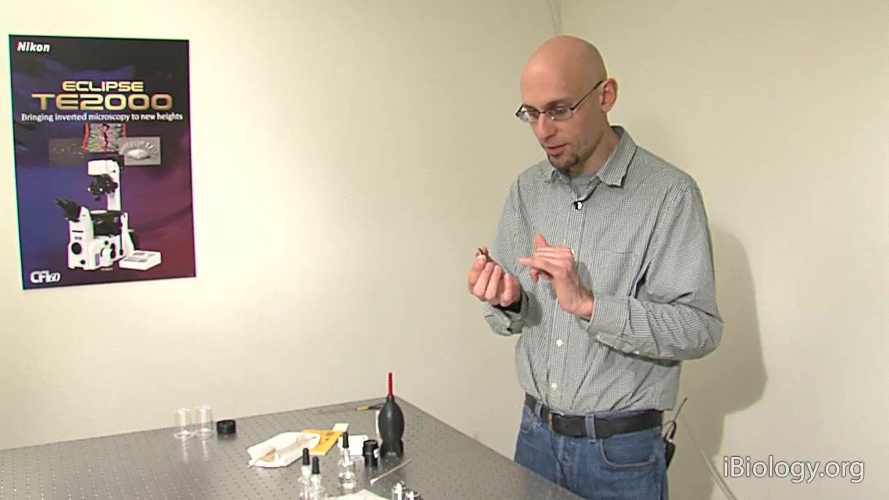 A person holds a mounted filter in a black ring and explains its structure.