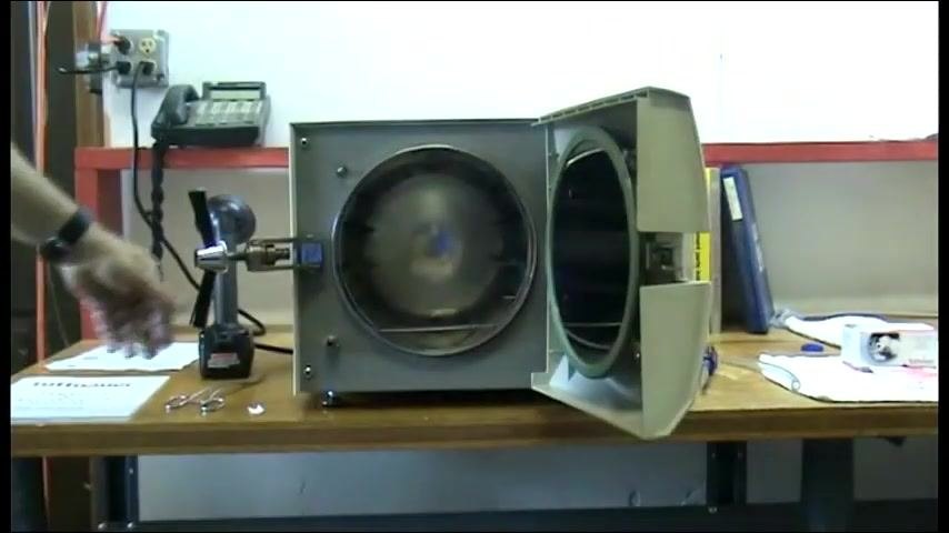 The autoclave door open, chamber visible, and the operator preparing for the next step.
