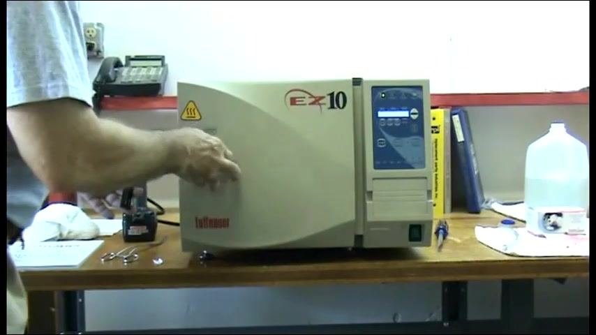 A person closing the autoclave door, with the EZ-10 logo visible and the control panel illuminated.