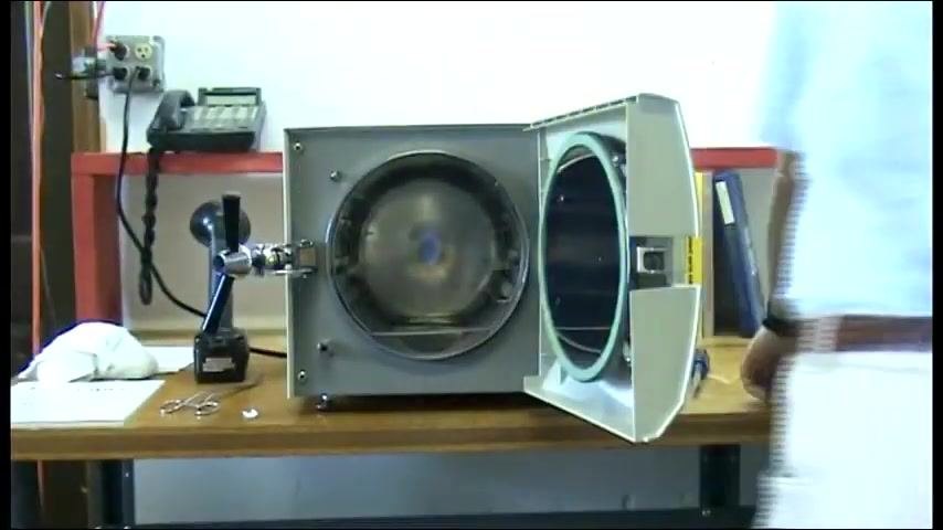 The autoclave running with the door locked and the control panel illuminated.