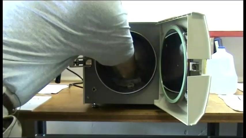 A person reaching into the chamber with a cloth to clean around the water sensor.