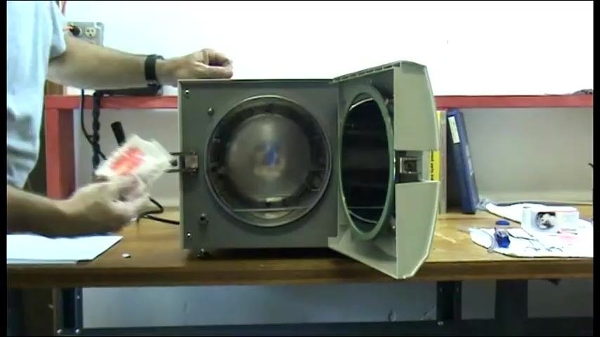 The chamber open with the operator holding a Chamber Brite packet, preparing to pour it in.