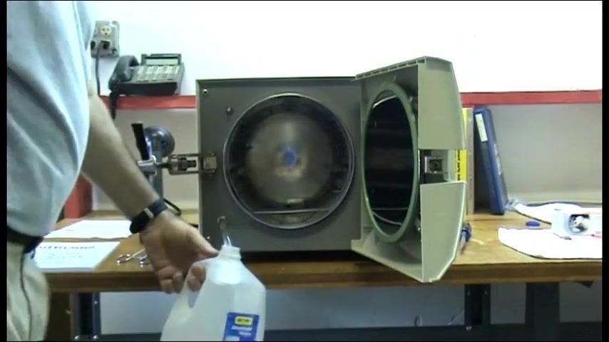 The operator connecting the drain hose and positioning a distilled water jug under the outlet as a collection container.