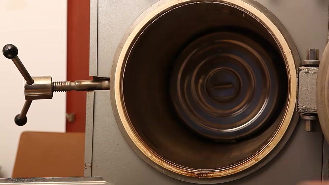 A laboratory autoclave shown as a vertical, metallic device with a control knob and indicator window, standing on wheels in a sterile environment