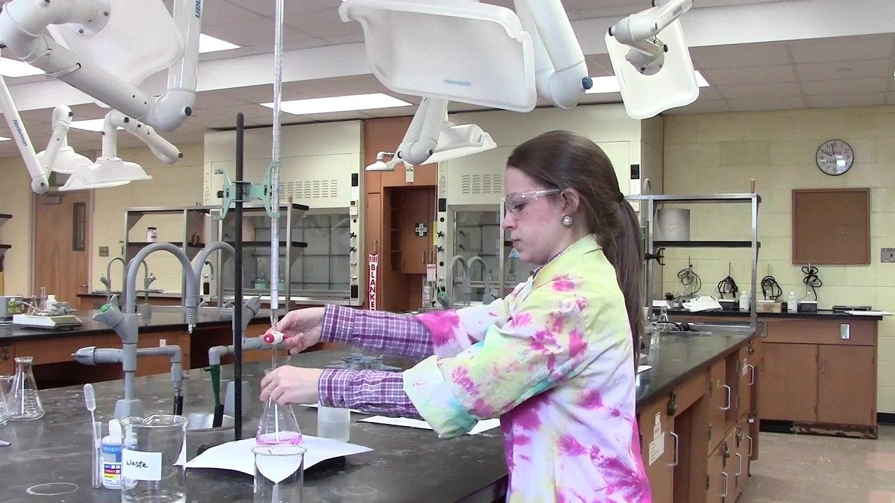 Person observing the flask as the pink color persists, indicating the endpoint is near.