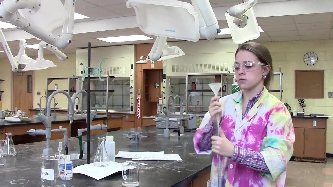 Person filling the burette with solution using a funnel.