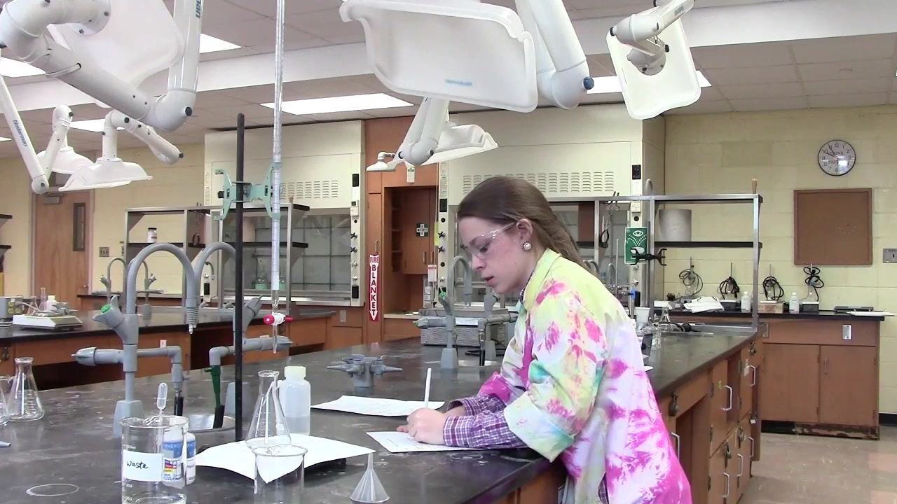 Person recording the initial burette reading at the lab bench.