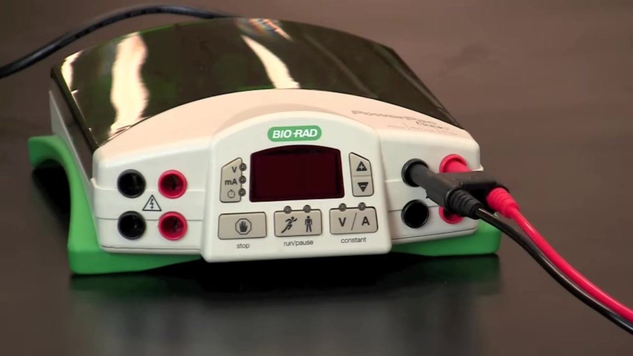 Close-up of the power supply display showing 9, with a gloved hand pressing the button to start the run