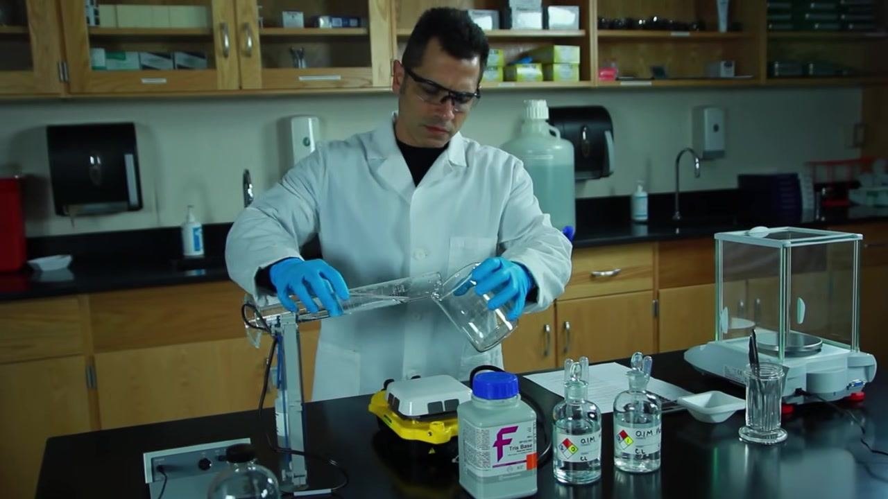 Gloved hands in a lab coat pouring water from a graduated cylinder into a 600 mL beaker