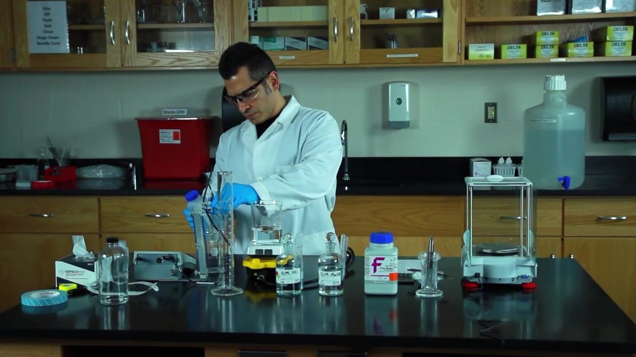 Removing the pH probe from the beaker at the lab bench, surrounded by bottles and equipment