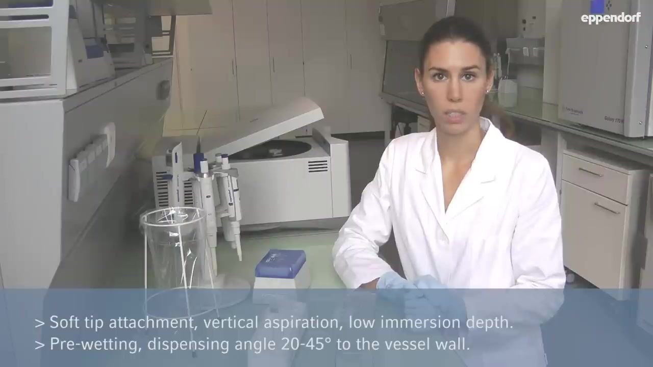 A person in a lab coat and gloves pressing the pipette control button, demonstrating the blowout step at the vessel wall