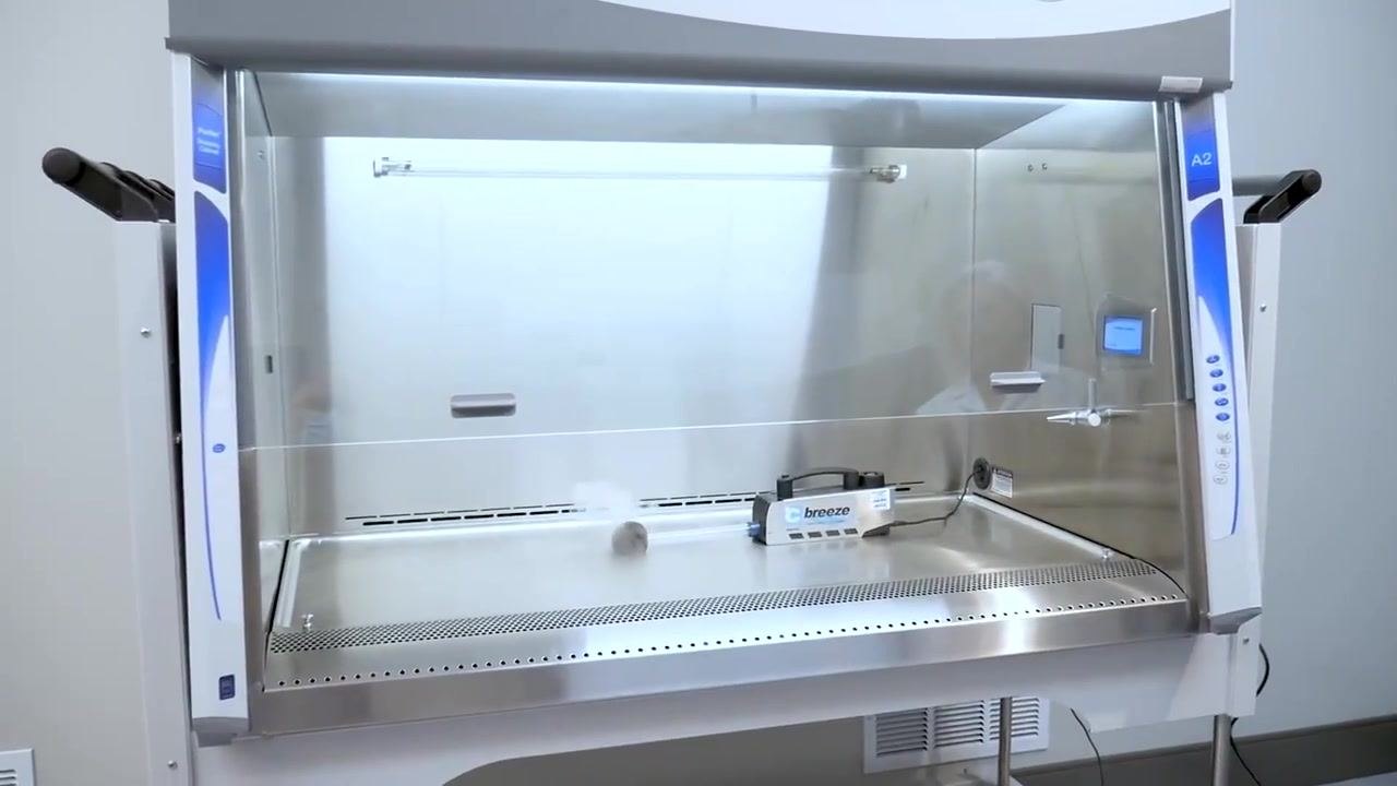 A worker stands next to the cabinet as an on-screen timer shows a five-minute countdown for equilibration and purging.