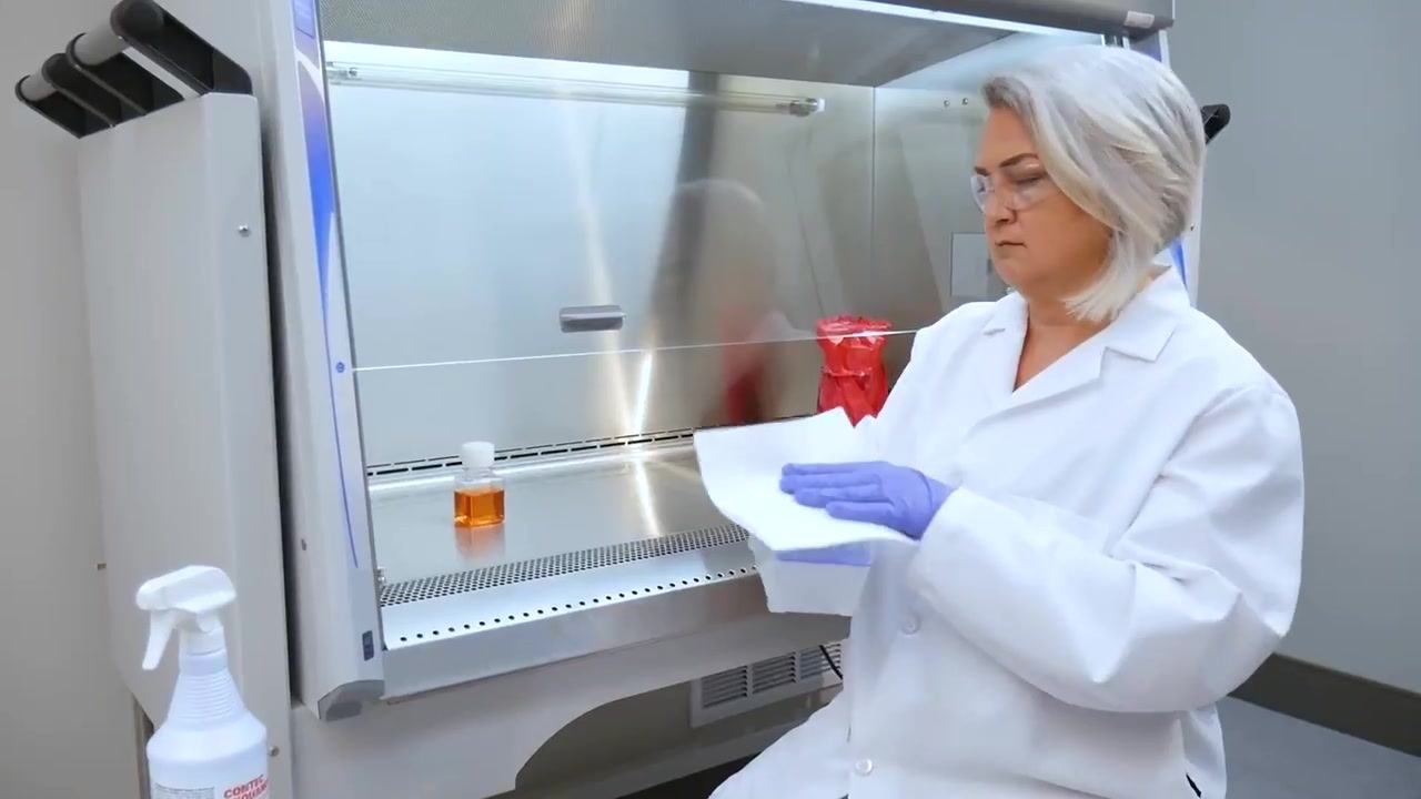A worker places a bottle of liquid inside the cabinet after wiping it down.