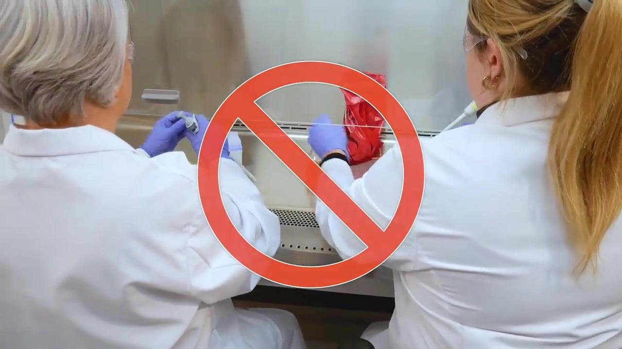 A gloved hand reaches for a disinfectant spray bottle inside the cabinet, with a biohazard bag and containers nearby.