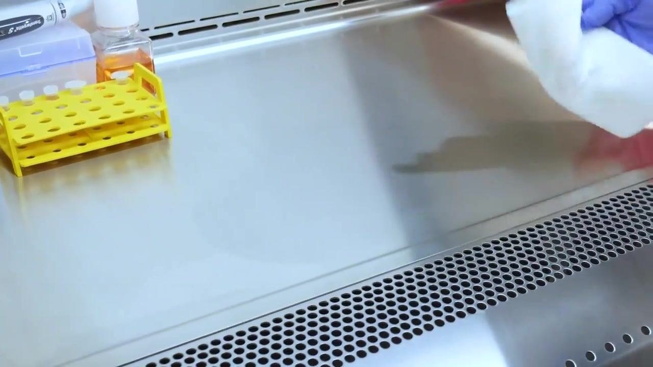 A gloved hand wipes the stainless steel surface to clean up the spill area.
