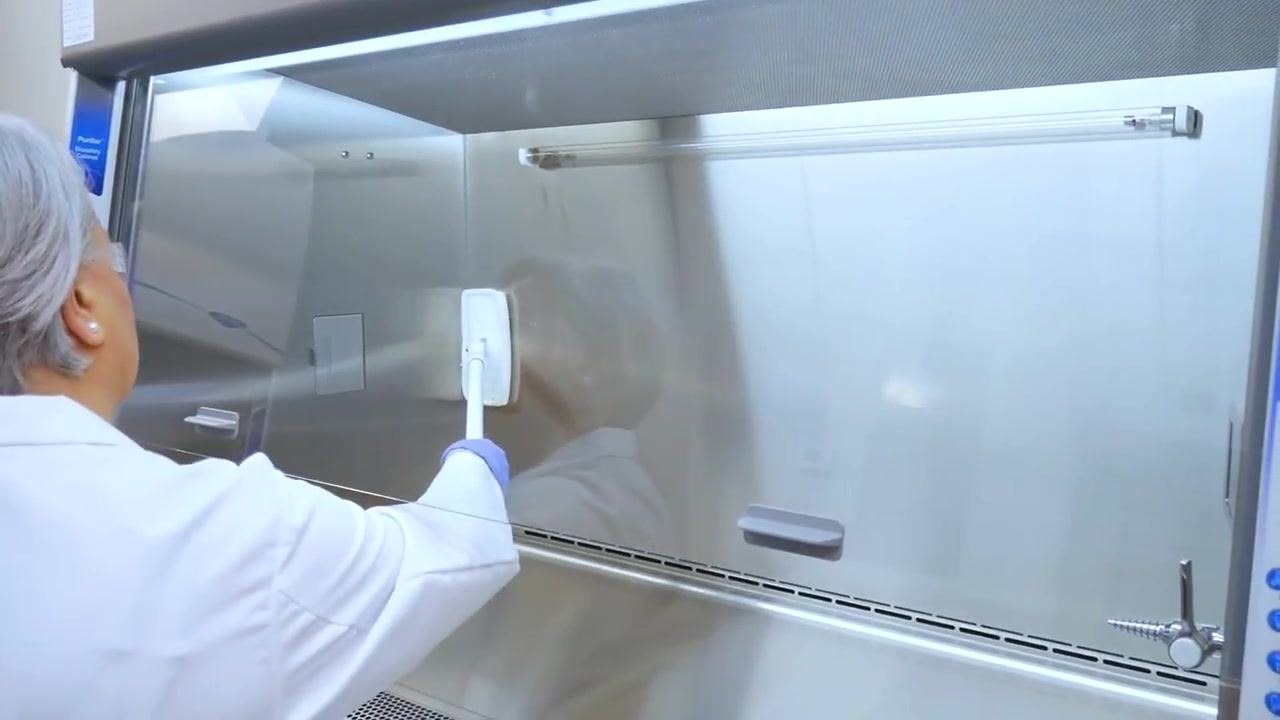 A worker uses a cleaning tool to wipe down the back wall and interior surfaces of the cabinet.