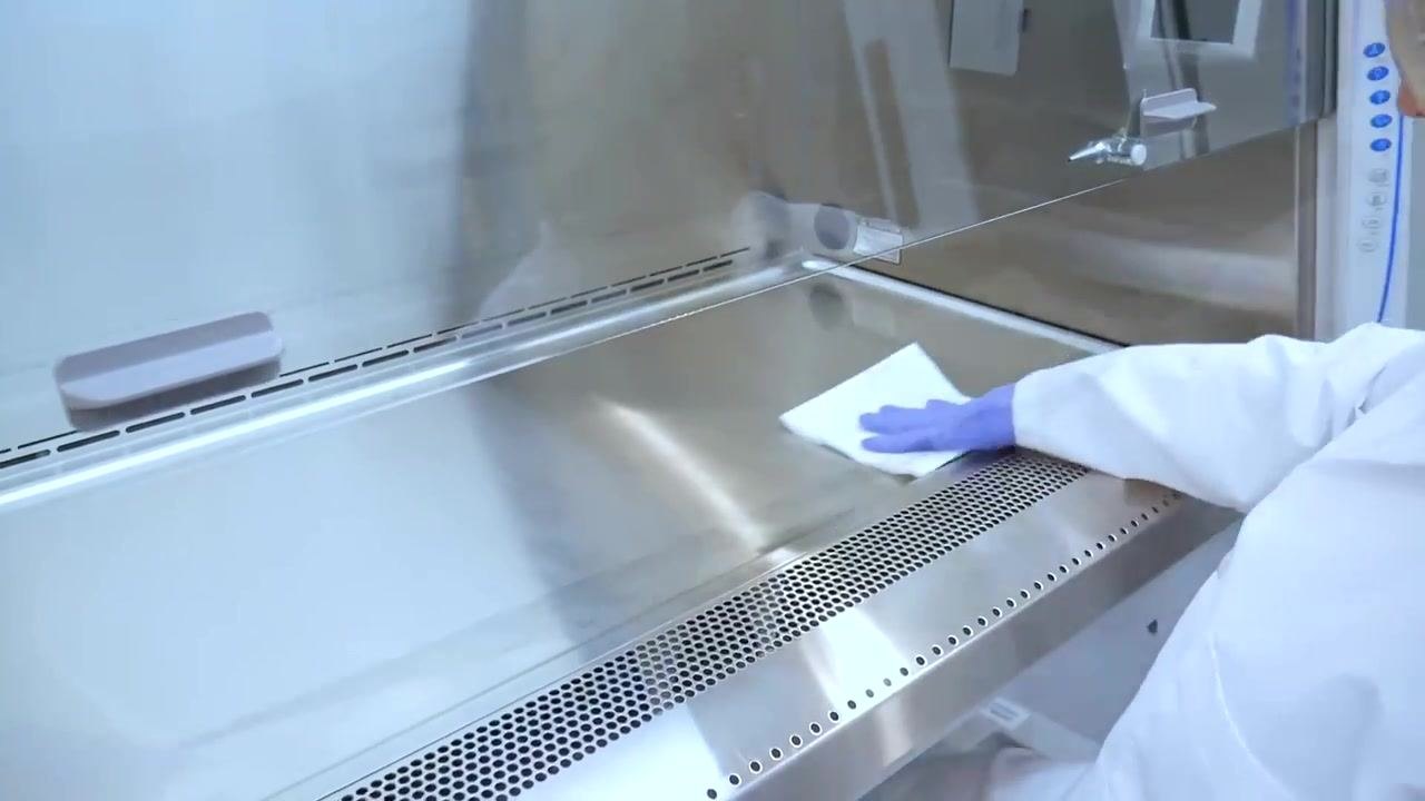 A worker wipes the stainless steel work surface before lifting it for extended cleaning.