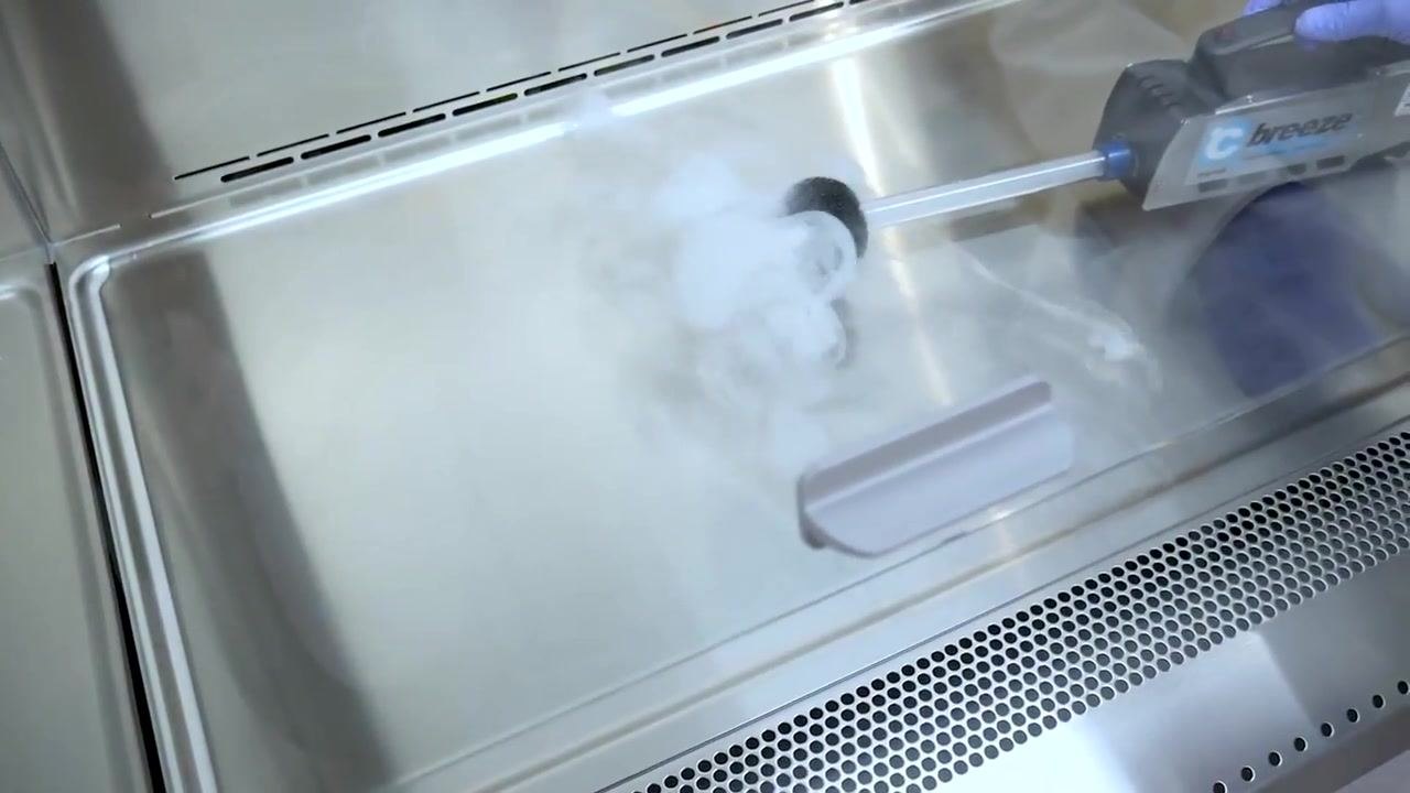 A gloved hand uses an airflow visualizer inside the cabinet to check for leaks and confirm proper airflow.