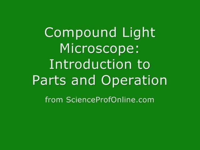 A compound light microscope on a lab table with the dust cover being removed. Laboratory setting with multiple microscopes in the background.