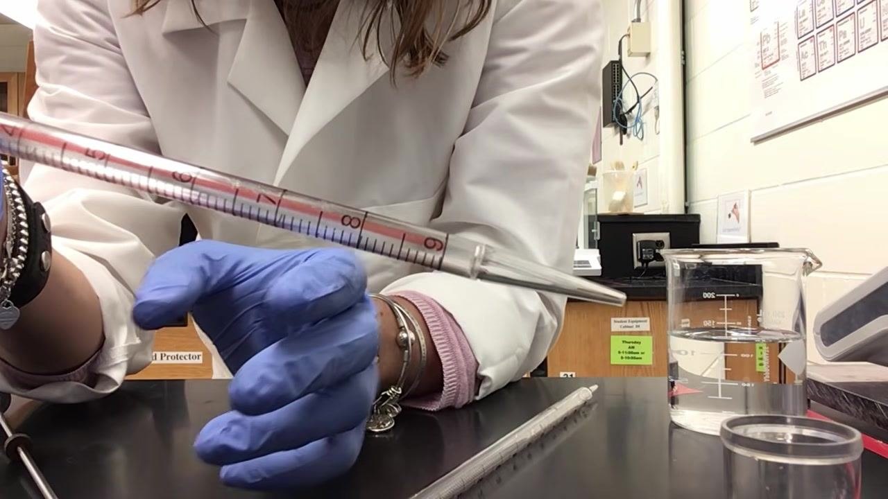 Close-up of a pipette tip and the 9 mL marking, with a hand pointing at the tip