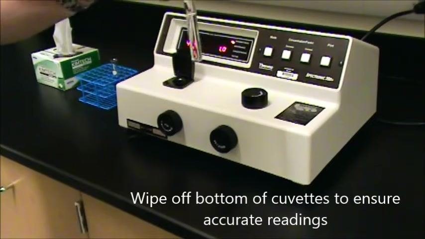 Hand wiping the bottom of a cuvette above the open sample compartment