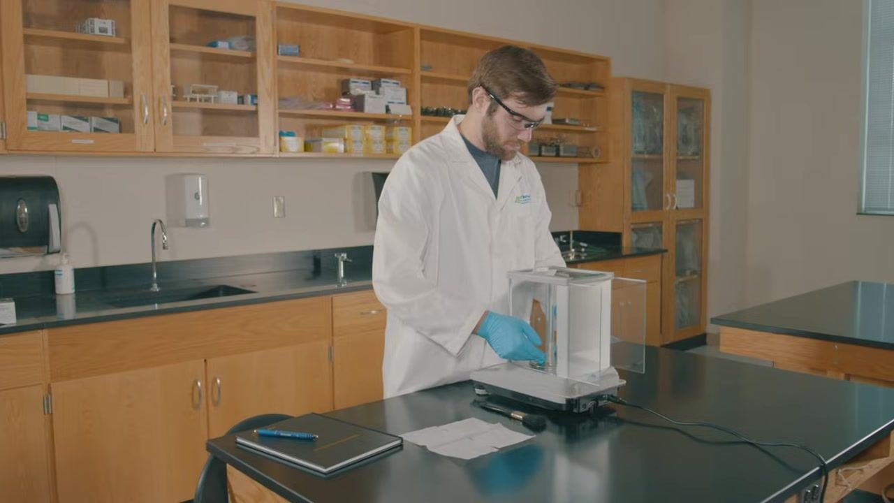 Lab technician removing the weigh pan and components from the analytical balance