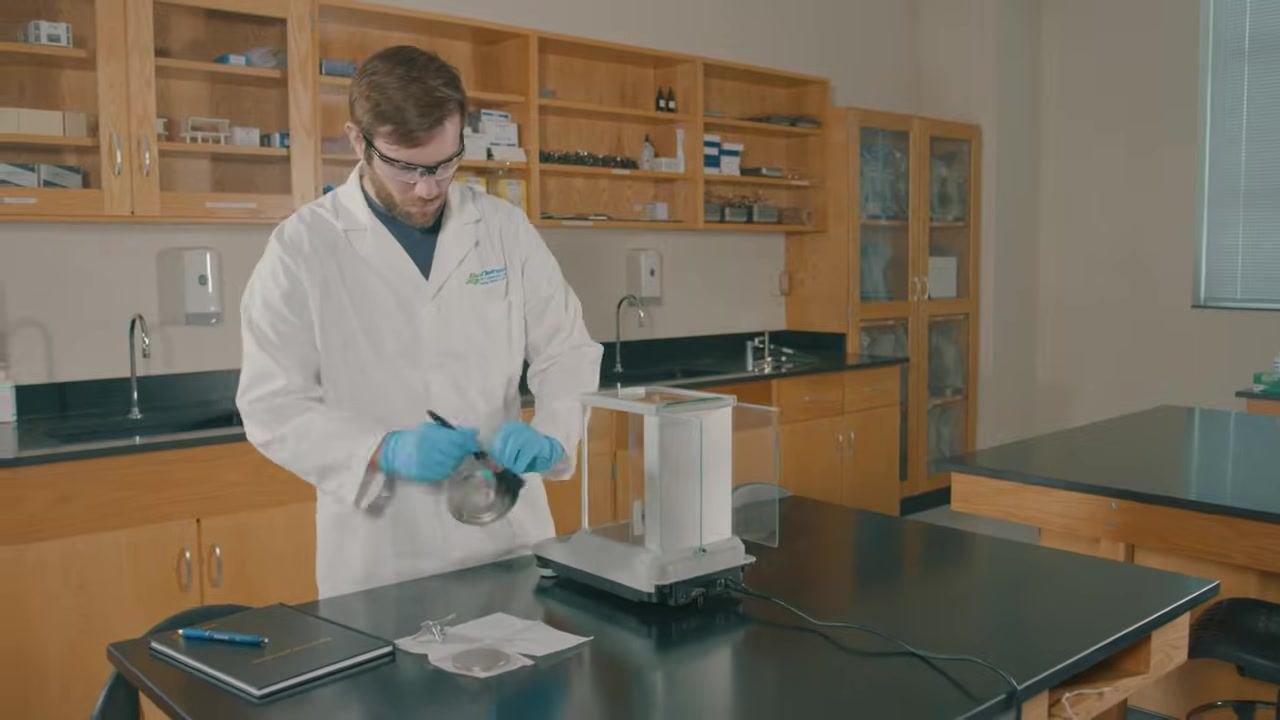 Lab technician replacing the drip ring and weigh pan after cleaning the analytical balance