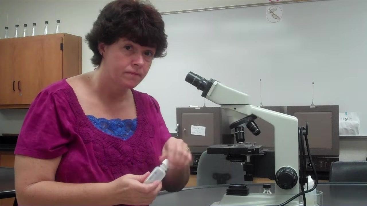 Instructor holding the recapped oil bottle, demonstrating safe handling after oil application.