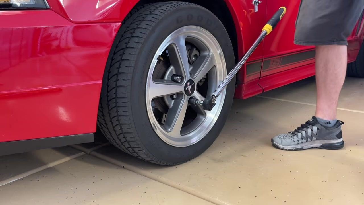 The torque wrench with extension and socket attached, positioned near the wheel and ready to use.