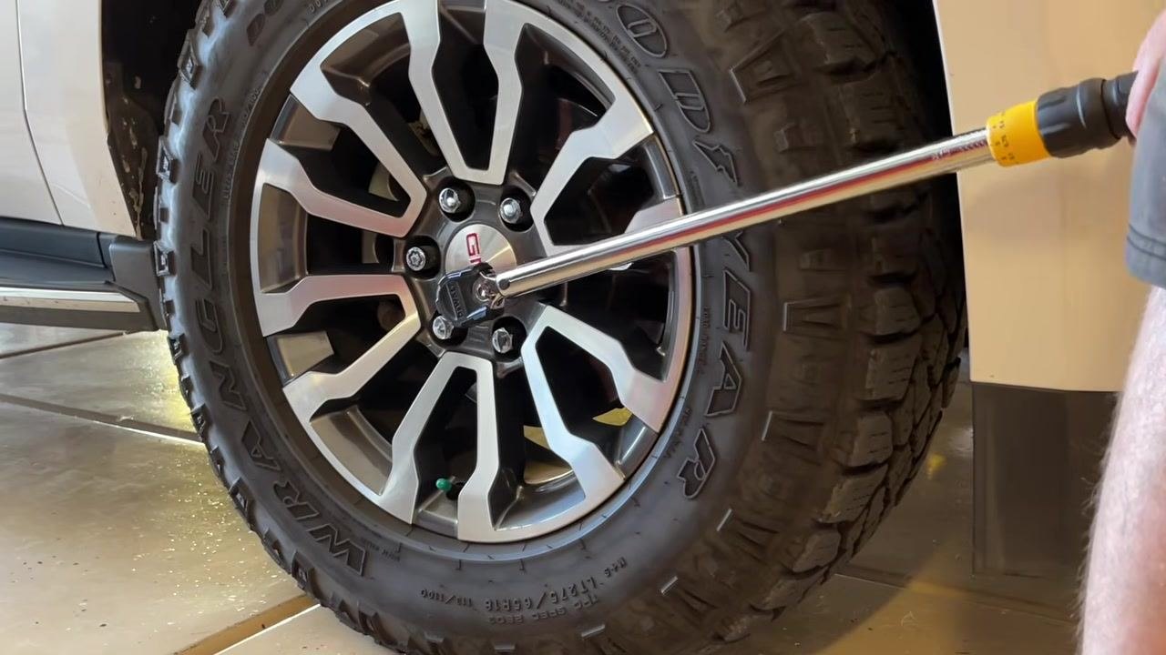 Torque wrench being used on a lug nut, with the user applying force to tighten it.