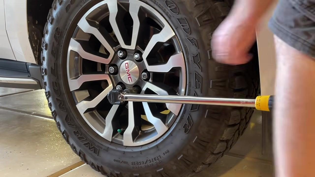 Torque wrench on a lug nut, with the user's hand off the wrench after tightening, showing the process is complete for that nut.
