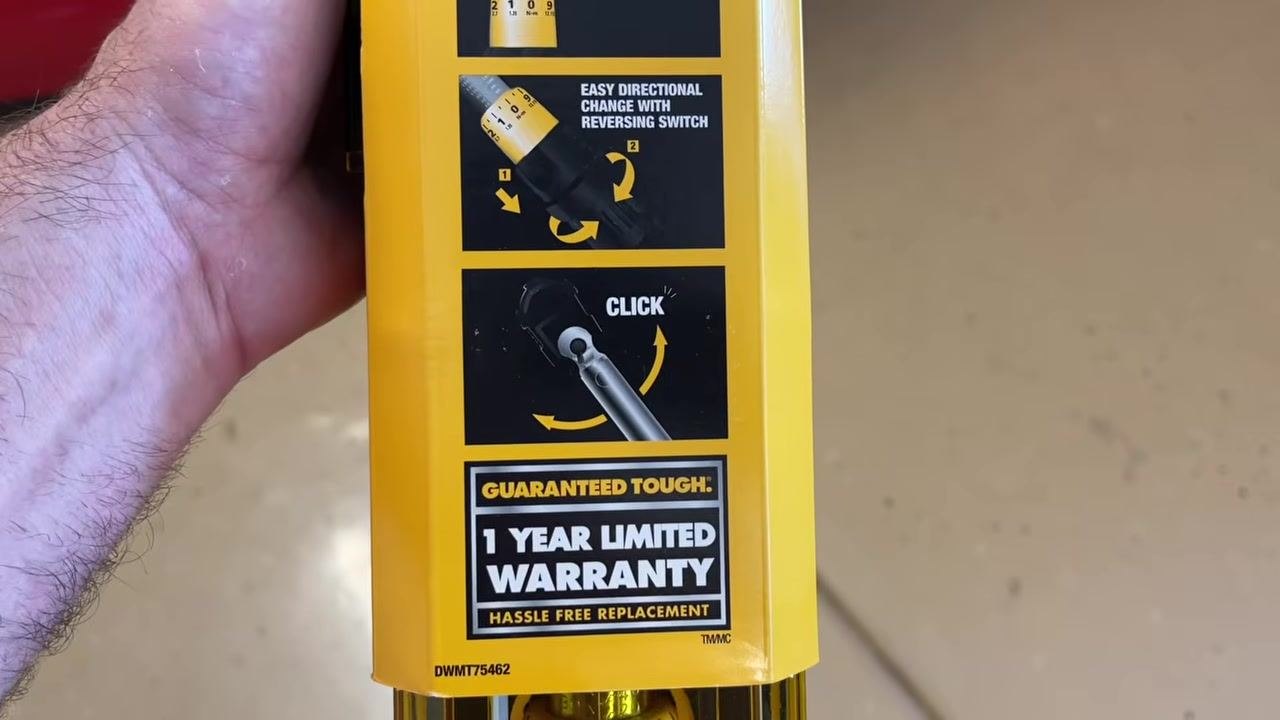 DeWalt torque wrench in its yellow plastic case, placed on a garage floor with a car visible in the background.