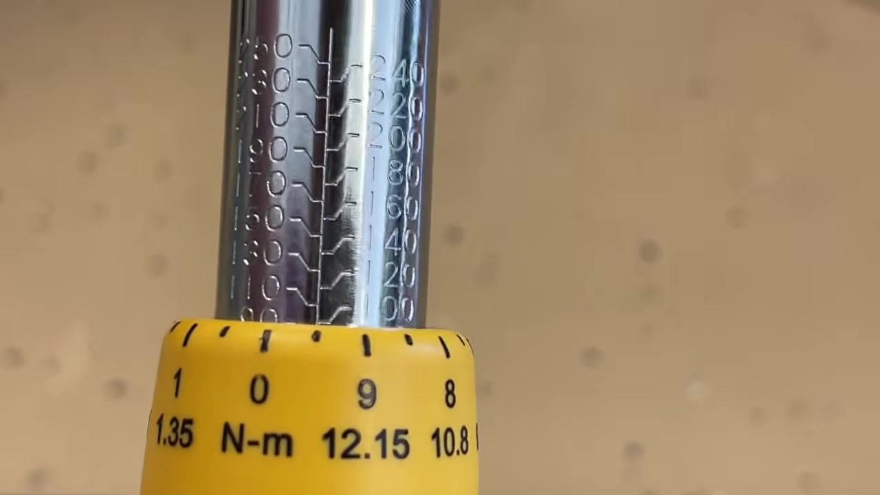 Torque wrench with the adjustment dial rotated so the 100 ft-lb mark is aligned at the top, and the zero mark on the dial aligns with the drop-down line.